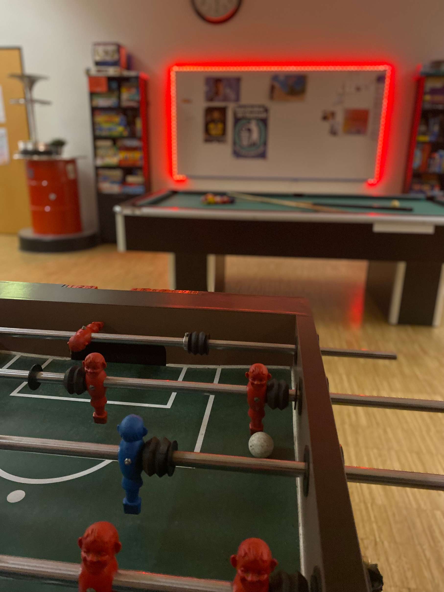 auf diesem Bild ist ein Billiardtisch im Hintergrund und ein Kicker im Vordergrund zu sehen.